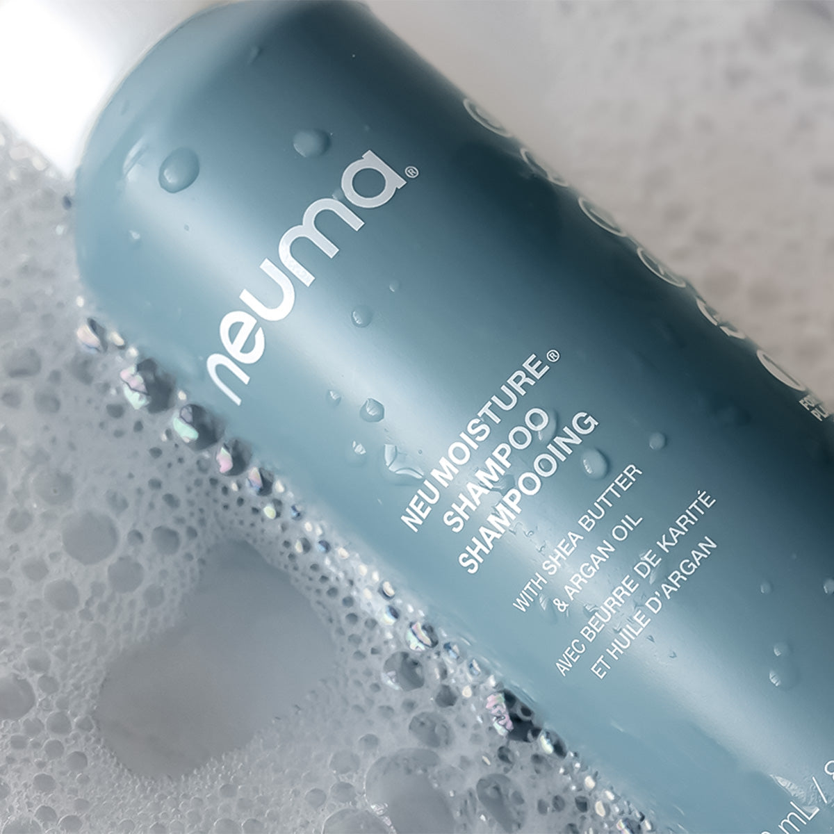 Neuma Moisture Shampoo bottle with bubbles, featuring shea butter and argan oil for hydrating hair care.