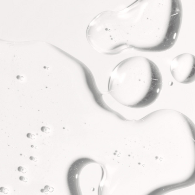 Close-up of hyaluronic self tanning serum showing clear, hydrating gel texture with bubbles and droplets.