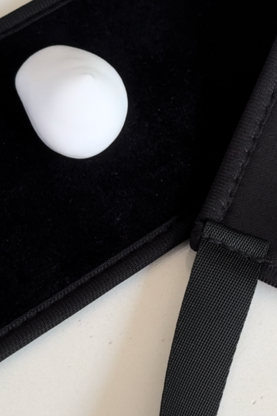 Close-up of a self tan back applicator with a smooth, white applicator on a black velvet background.