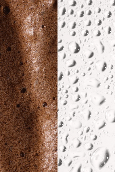 Close-up of rich brown foam beside droplets of water, showcasing texture variations for beauty or skincare imagery.