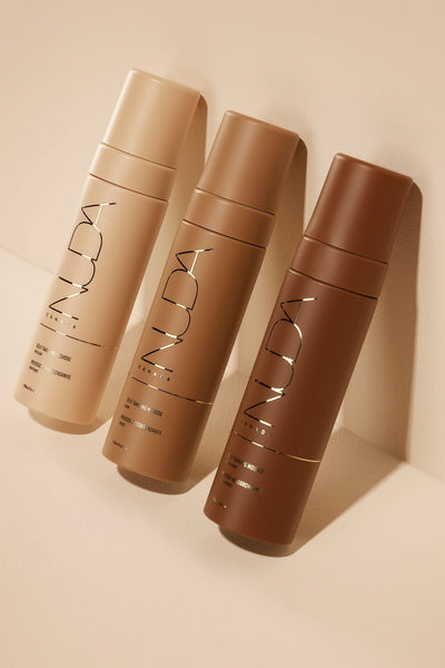 Three self-tanning mousse bottles in light, medium, and dark shades for customizable tanning.