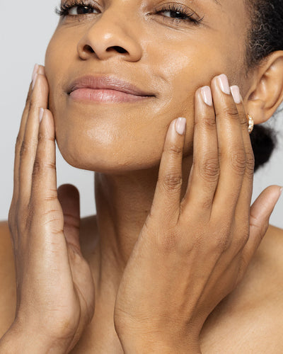 woman applying skin lightening serum to her face, showcasing glowing and healthy skin.