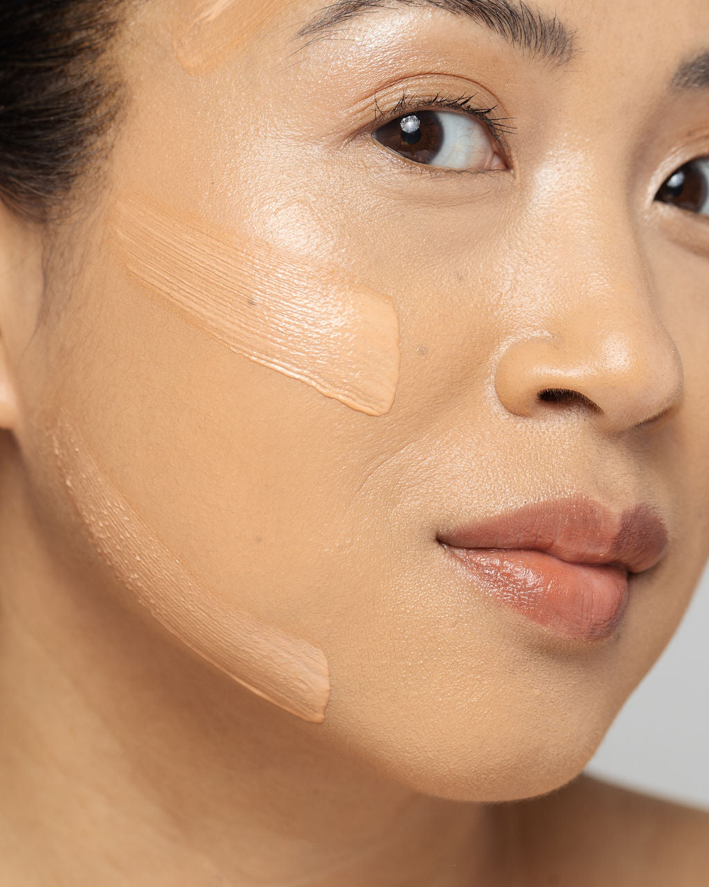 Close-up of a woman applying a creamy clay mask to her face, showcasing skincare treatment for healthy, glowing skin.