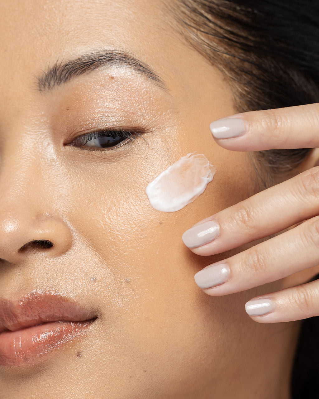 Woman applying Vivier Daily Age-Defying Moisturizer to her face, showcasing a smooth and radiant complexion.