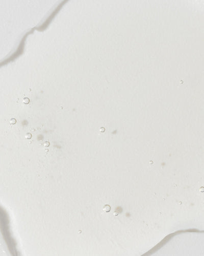 Close-up of GrenzCine Serum showing a clear, gel-like texture with tiny bubbles, highlighting its moisturizing properties.