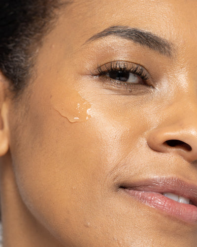 Close-up of a woman with glowing skin applying a gentle gel cleanser for all skin types.