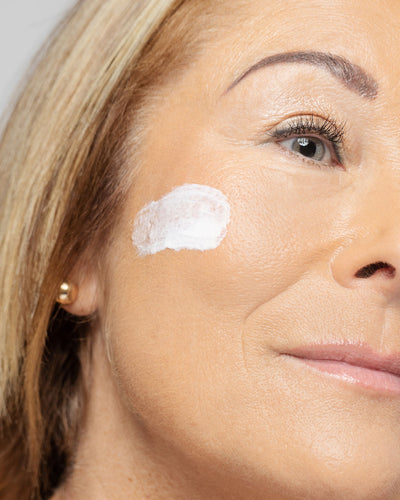 woman applying Vivier Retinol 0.3% cream on her cheek, showcasing skincare routine for improved texture and tone.