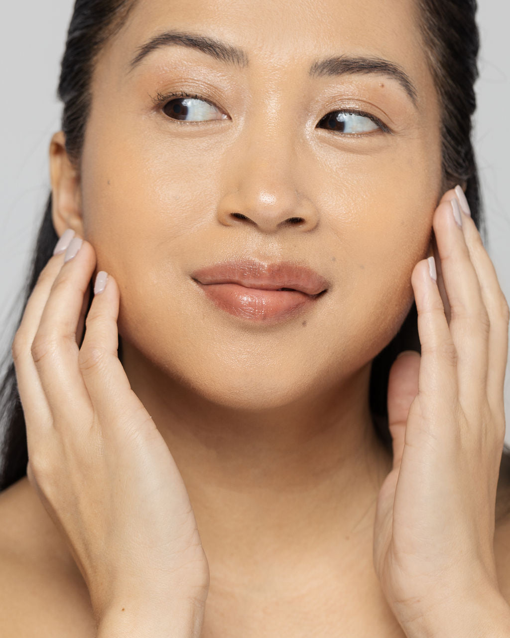 woman gently applying skincare to her clean, radiant face showcasing the benefits of a revitalizing Vitamin C scrub.