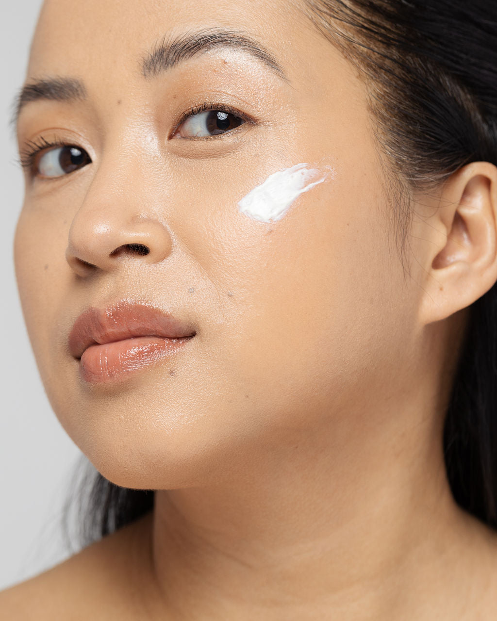 Woman applying dermatologist-grade retinol cream on her cheek for anti-aging benefits and improved skin texture.