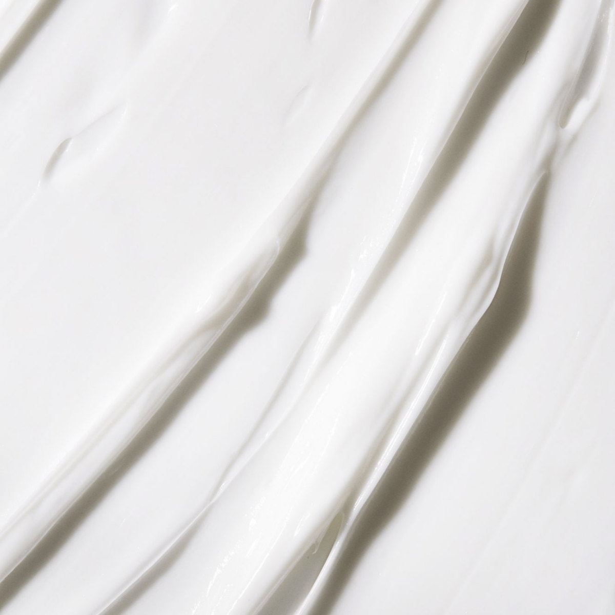 Close-up of creamy white texture of body cream, highlighting its rich and nourishing formula for soft, hydrated skin.