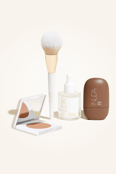 Deluxe Bronzed Kit featuring facial tanner, bronzing powder, brush, and glow drops for a radiant complexion.