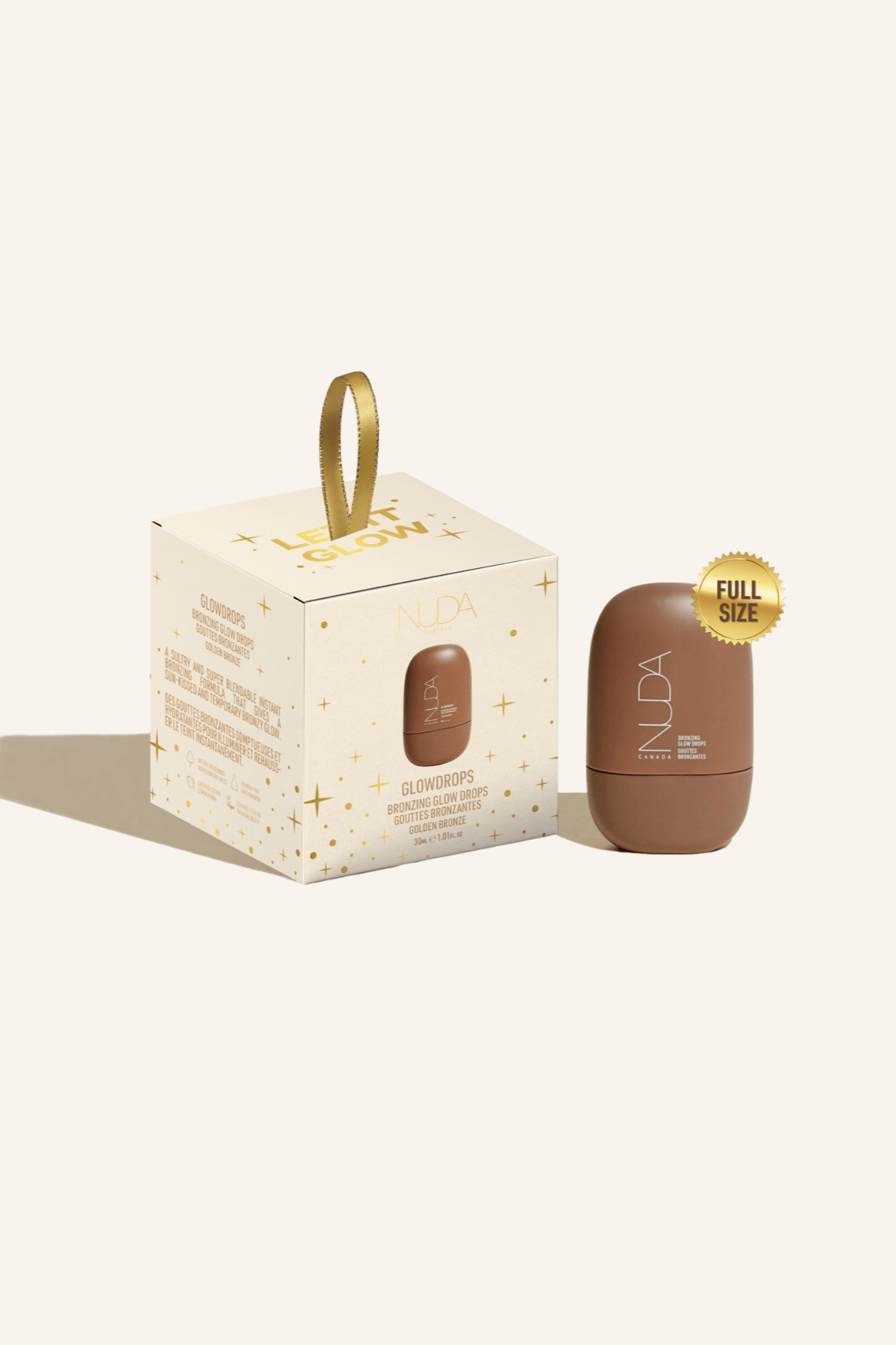 Nuda Let It Glow Ornament featuring full-size Bronzing Glow Drops in a festive package with a gold ribbon.