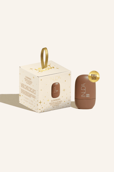 Nuda Let It Glow Ornament featuring full-size Bronzing Glow Drops in a festive package with a gold ribbon.