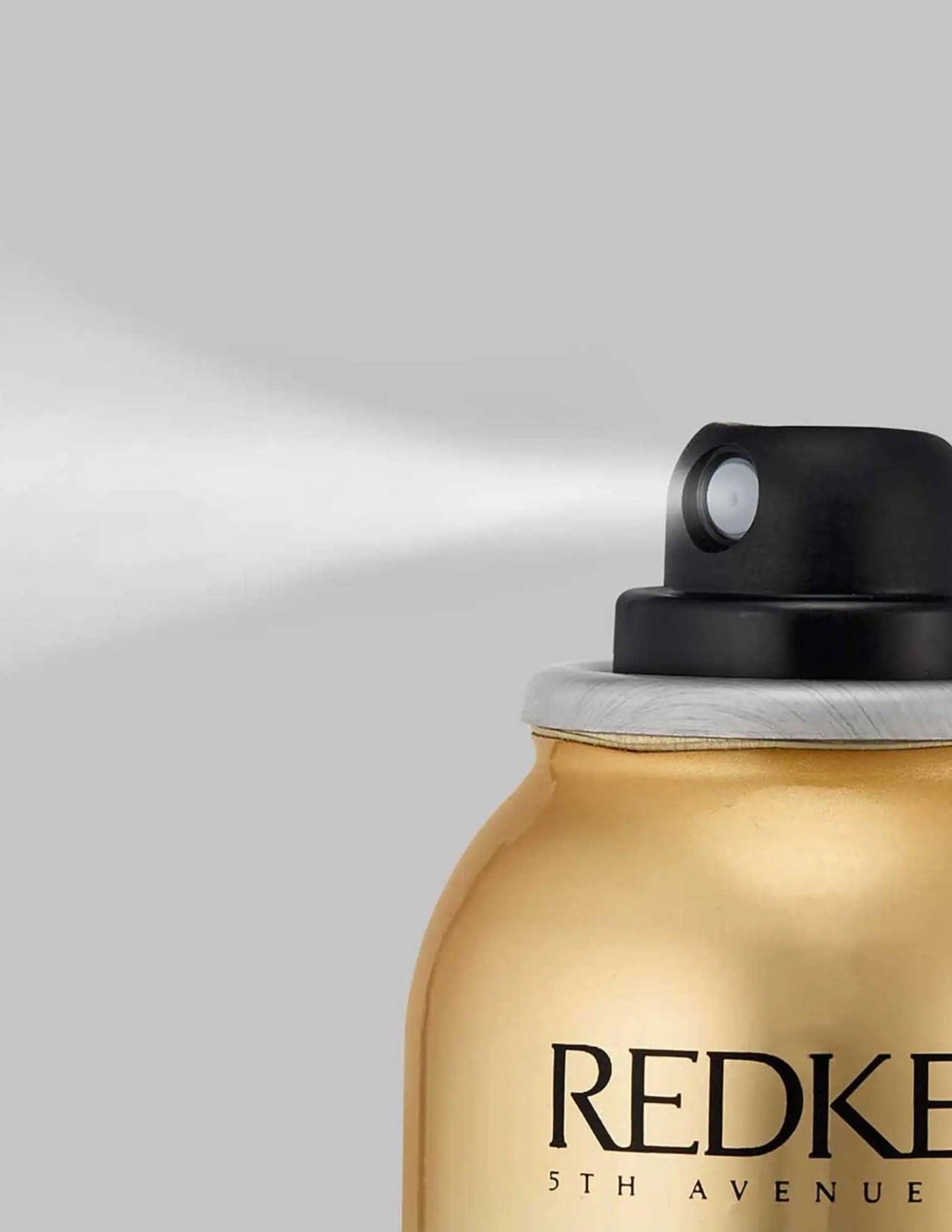 Redken Shine Flash spray bottle releasing fine mist for radiant hair shine and smooth finish.