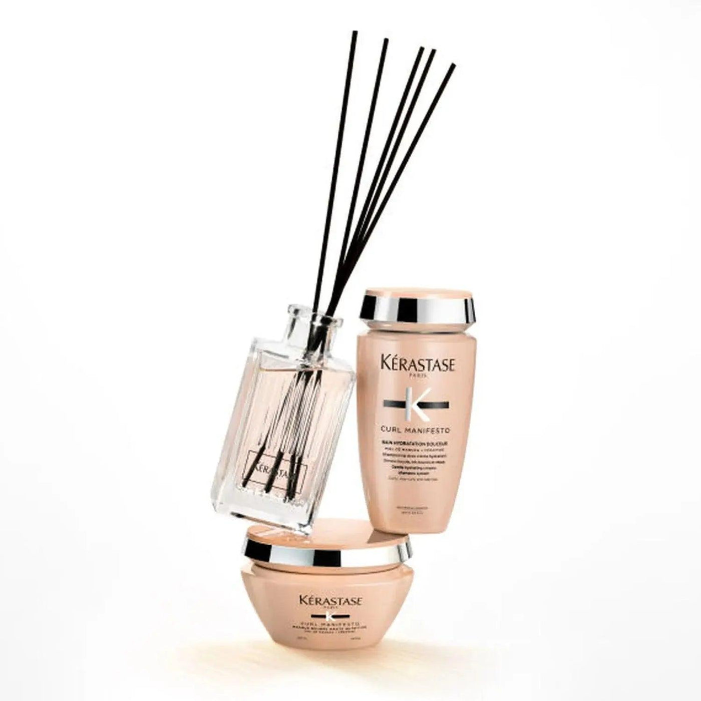 Kérastase Curl Manifesto home fragrance and conditioners in elegant packaging with diffuser sticks on a white background.