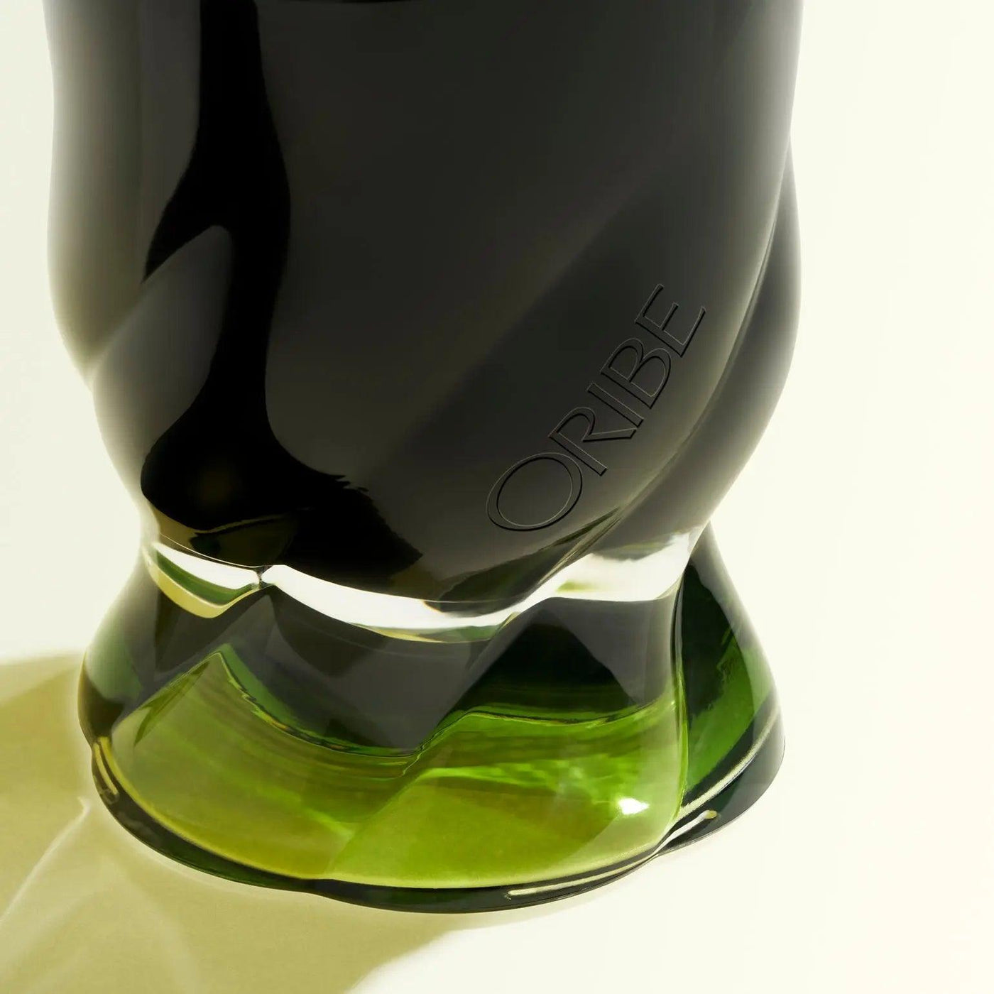 Close-up of Oribe Desertland scented candle showcasing its elegant black and green glass design.